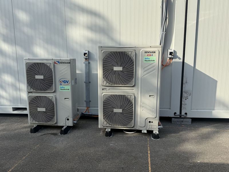 Zwei Aussengeräte eines VRF-Klimasystems an einer Gebäudefassade, mit dem Firmenaufkleber von Infra Haustechnik